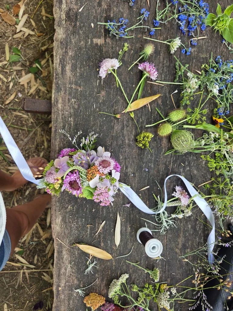 Selbst gebundener Blumenkranz mit Bändern auf einem Holztisch